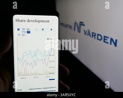 In questa immagine, una persona ha in mano uno smartphone con il sito web della società di investimento svedese Industrivarden AB sullo schermo davanti al logo. Foto Stock