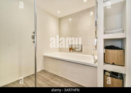 Un bagno elegante e contemporaneo con cabina doccia, vasca e arredamento minimalista che enfatizza la funzionalità e lo stile in un ambiente incontaminato. Foto Stock