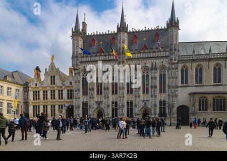 La facciata gotica ornata del municipio di Bruges si erge maestosamente in piazza Burg, affollata di visitatori in parte Foto Stock