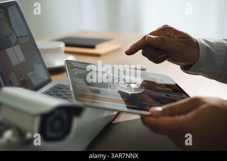 Sistema di sicurezza cctv, uomo che monitora in ufficio da smartphone riprese della fotocamera sullo schermo Foto Stock