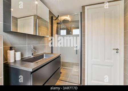 Un bagno contemporaneo con cabina doccia, elegante lavabo e illuminazione elegante, che mette in risalto elementi di design e funzionalità moderni. Foto Stock