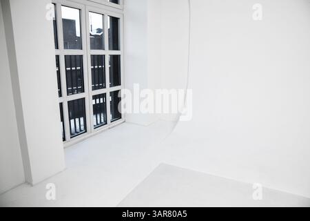 Camera bianca luminosa e spaziosa con cyclorama, con grandi finestre in vetro, che offrono un fascino minimalista e moderno, ideale per spazi di lavoro creativi Foto Stock