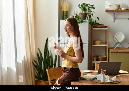 Una giovane donna ama il caffè nella sua cucina moderna, abbracciando la calma luce del mattino. Foto Stock