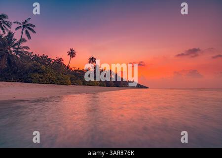 Profilo di palme lungo la spiaggia tropicale che si illumina di rosa arancione cielo al tramonto, mare calmo, luce calda, tranquilla isola paradisiaca. Paesaggio di viaggio mozzafiato Foto Stock