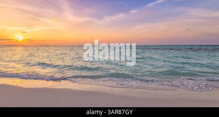 Vista panoramica del tramonto sulla spiaggia, cielo dorato che si illumina all'orizzonte, calmo litorale tropicale dell'oceano. Tranquillo, caldo sole, sereno paradiso per le vacanze. Ispirare la natura Foto Stock