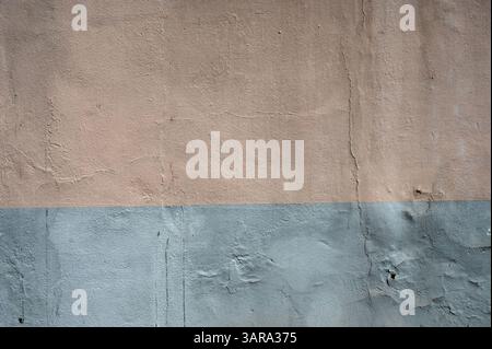 Parete in cemento intemprato verniciata in due tonalità, beige e grigio, con sfondo testurizzato ideale per progetti di design Foto Stock