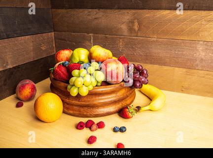 Raccolta di frutta STILL Life in una ciotola di legno su uno sfondo di tavole di legno rustiche Foto Stock