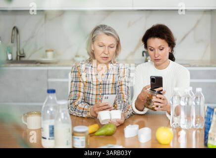 Due donne che scansionano prodotti diversi utilizzando il proprio smartphone Foto Stock