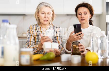 Due donne che scansionano prodotti diversi utilizzando il proprio smartphone Foto Stock