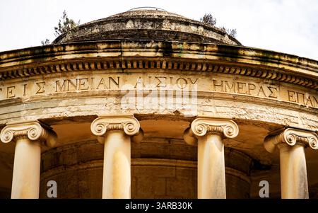 Vista ravvicinata di antiche colonne in pietra e di una struttura circolare con iscrizioni greche, che mostra l'architettura classica e il significato storico Foto Stock
