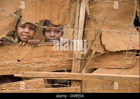 1 settembre 2009 - Nairobi, Kenya - due bambini giocano dietro un muro di metallo ondulato nell'insediamento informale Kibera a Nairobi, Kenya. Più di un milione di persone affollano la baraccopoli, che si trova a circa 5 km dal centro di Nairobi in Kenya (immagine di credito: © David Snyder/ZUMA Press) Foto Stock