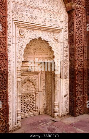 Pannello di mihrab decorato con calligrafia cufica nella tomba di Iltutmish, complesso Qutb Minar, Delhi, che fonde motivi geometrici e floreali a reticolo di pietra. Foto Stock
