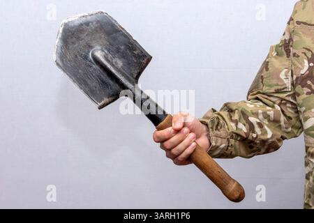 Un soldato con un'uniforme militare americana tiene una pala di sapone tra le mani su uno sfondo chiaro Foto Stock