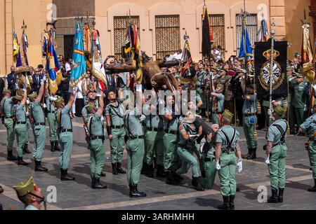 Un gruppo di legionari trasporta il Cristo di Mena durante il trasferimento del Cristo di Mena il giovedì Santo, una delle processioni della settimana Santa più famose di tutta la Spagna, sia per ciò che rappresenta sia per la partecipazione della Legione che canta "El Novio de la Muerte", un canto emblematico diventato l'inno non ufficiale della Legione spagnola. Foto Stock