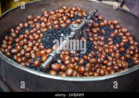 Arrostire le castagne con il carbone Foto Stock