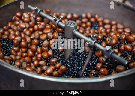 Arrostire le castagne con il carbone Foto Stock