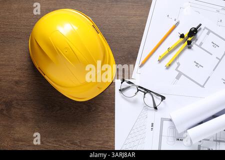 Diversi disegni architettonici, elmetto, matita, divisore e vetri su tavolo in legno, piatto Foto Stock