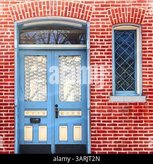 Doppia porta blu vintage con tende in pizzo e una finestra con pannelli diamantati, adagiata su una vibrante facciata in mattoni rossi a Chicago Foto Stock