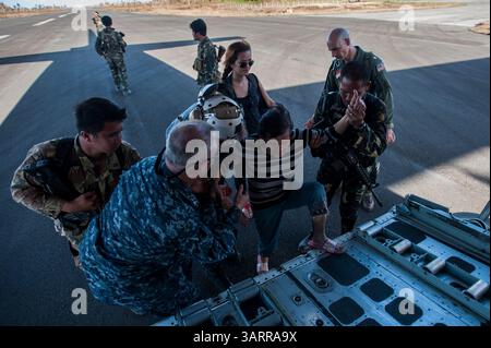 15 novembre 2013 - Samar, Filippine - i marinai e i soldati dell'esercito filippino aiutano una donna a salire sull'aereo per essere trasportata in aereo in un luogo più sicuro. La portaerei USS George Washington è arrivata nelle Filippine per unirsi alla risposta internazionale di soccorso al tifone catastrofico che ha colpito la settimana scorsa, causando più di 2.000 vittime. (Immagine di credito: © Liam Kennedy/U.S. Navy/ZUMAPRESS.com) Foto Stock