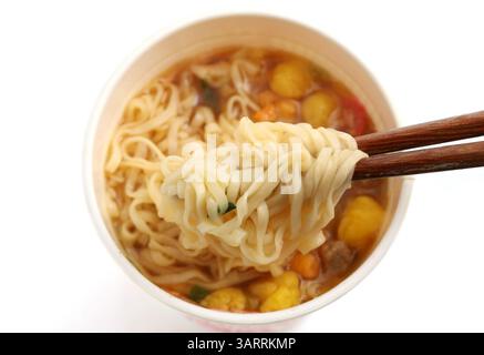 mangiare spaghetti istantanei bolliti in una tazza di plastica con bacchette Foto Stock