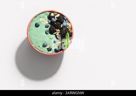 Ciotola con frullato di spirulina e frutti di bosco su sfondo bianco Foto Stock