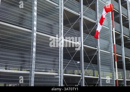 Vento rosso e bianco che indica la direzione del vento vicino a un edificio moderno con una facciata in rete metallica Foto Stock