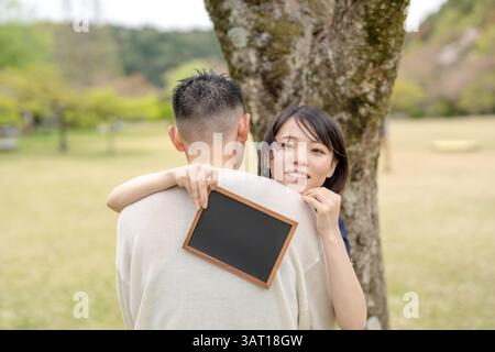Nella scena primaverile di maggio, c'è un parco senza equipaggio, la prefettura di Aichi. Le coppie giapponesi nei primi anni '20 trascorrono del tempo insieme. Abbracciano ognuno di loro Foto Stock