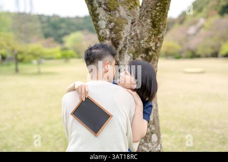 Nella scena primaverile di maggio, c'è un parco senza equipaggio, la prefettura di Aichi. Le coppie giapponesi nei primi anni '20 trascorrono del tempo insieme. Abbracciano ognuno di loro Foto Stock