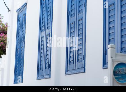 Persiane di legno blu in un edificio greco bianco, che mostra l'architettura delle Cicladi con audaci contrasto di colore e tradizionale stile isolano in un classico Ae Foto Stock