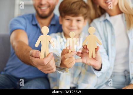 Famiglia felice con bambino che tiene a casa le figure di legno Foto Stock