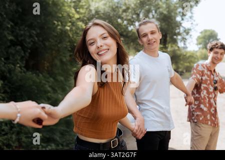 Giovani amici felici che si tengono per mano nel parco estivo Foto Stock