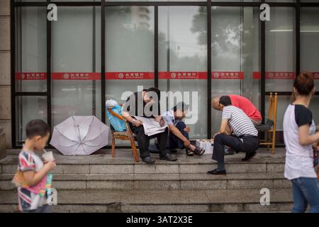 15 luglio 2013 - Pechino, Cina - dopo una pioggia battente, alcune persone si siedono di fronte alla Banca di Pechino a suonare lo scacchi cinese o a leggere il giornale a Dongsi Shitiao, Pechino. (Immagine di credito: © Jiwei Han/ZUMAPRESS.com) Foto Stock