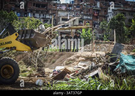 21 luglio 2013 - Caracas, Miranda, Venezuela - Un trattore rimuove alcune delle strutture temporanee che erano state costruite su un pezzo di terra conteso dopo l'arrivo dei membri della Guardia Nazionale venezuelana per rimuovere circa 200 persone che avevano occupato il terreno, sperando di costruirvi case. Il governo socialista dice che la proprietà di 10 ettari sarà il sito di una serie di edifici residenziali pubblici, un progetto che è stato avviato quattro anni fa ma deve ancora iniziare. Secondo un abitante, "vogliamo solo che il governo inizi a costruire, o che ci dia la terra e lo faremo tu Foto Stock