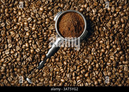 Vista dall'alto del portafiltro della macchina da caffè riempito con caffè appena macinato su chicchi torrefatti Foto Stock