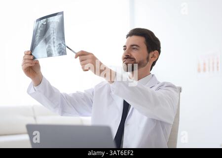 Medico sorridente che esamina la scansione RM del collo in clinica Foto Stock