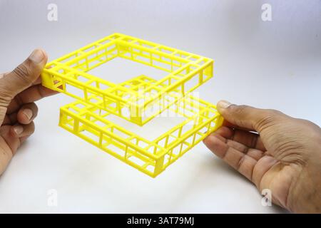 Oggetto di forma geo-metrica stampato in 3D tenuto in mano su sfondo bianco. Oggetti stampati con una stampante 3d. Foto Stock