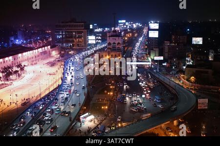 Un vivace paesaggio urbano di notte, che mostra edifici illuminati, strade trafficate piene di auto e vivaci cartelloni pubblicitari. La scena cattura l'energia di Foto Stock