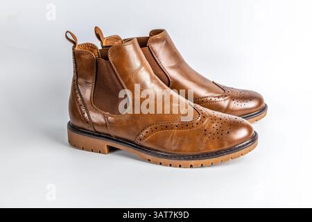 Primo piano di stivali Chelsea in pelle marrone con design a punta alata in brogue e suola robusta. Foto Stock