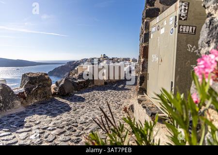 Santorini, Grecia - 15 ottobre 2024: Sentiero acciottolato a Oia con vedute panoramiche del Mar Egeo e degli iconici edifici bianchi di Santorini. Foto Stock