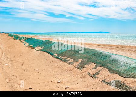 Fuoriuscita di olio combustibile in mare. Duna di sabbia di barriera ricoperta da rete protettiva per impedire che l'olio combustibile venga gettato a terra dalle onde. Disastro ecologico, metodi di elim Foto Stock