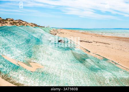Fuoriuscita di olio combustibile in mare. Duna di sabbia di barriera, coperta da rete protettiva dall'olio combustibile gettato a terra dalle onde. Catastrofe ecologica, metodi di elim Foto Stock