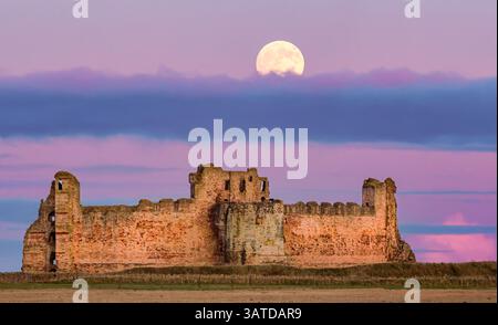 Luna piena che sorge sopra lo storico castello di Tantallon, Lothian orientale, Scozia, Regno Unito Foto Stock