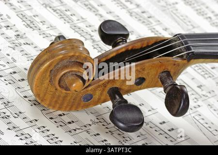 Maniglia di un vecchio violino su un foglio di note dettaglio di un vecchio violino su un foglio di note Foto Stock