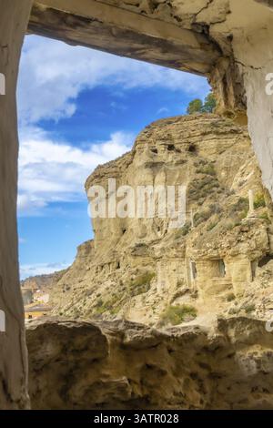 Scogliere di arenaria con abitazioni in grotta che si affacciano sul villaggio di arguedas in navarra, spagna, viste da una vecchia finestra Foto Stock