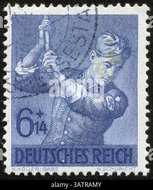 GERMANIA - CIRCA 1943: Un francobollo stampato dal fascista Germany Post è intitolato German Empire. Mostra un soldato che solleva qualche attrezzo, intorno al 1943 Foto Stock