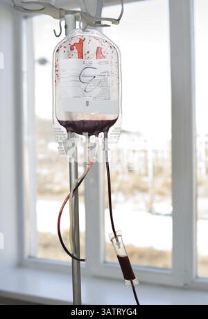 La confezione trasparente appesa al rack viene riempita con sangue del donatore Foto Stock