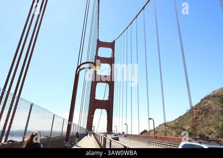 Colonna rossa luminosa del Golden Gate Bridge contro il cielo blu. Foto Stock