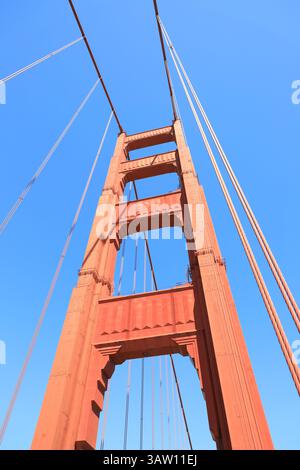 Colonna rossa luminosa del Golden Gate Bridge contro il cielo blu. Foto Stock