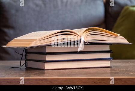 Un romanzo aperto si trova sopra una pila di libri chiusi Foto Stock