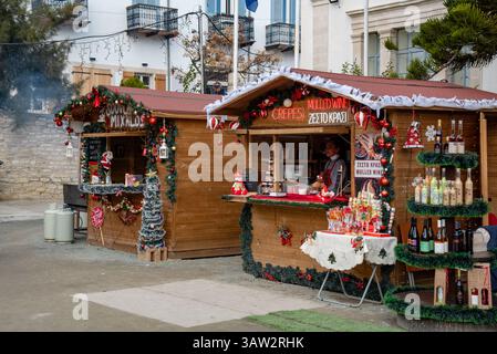 Lefkara, Cipro, dicembre 28 2024: Piccoli chioschi di legno che vendono VIN brulé, crepes e dolci al mercatino di natale con venditori che servono i clienti. Foto Stock